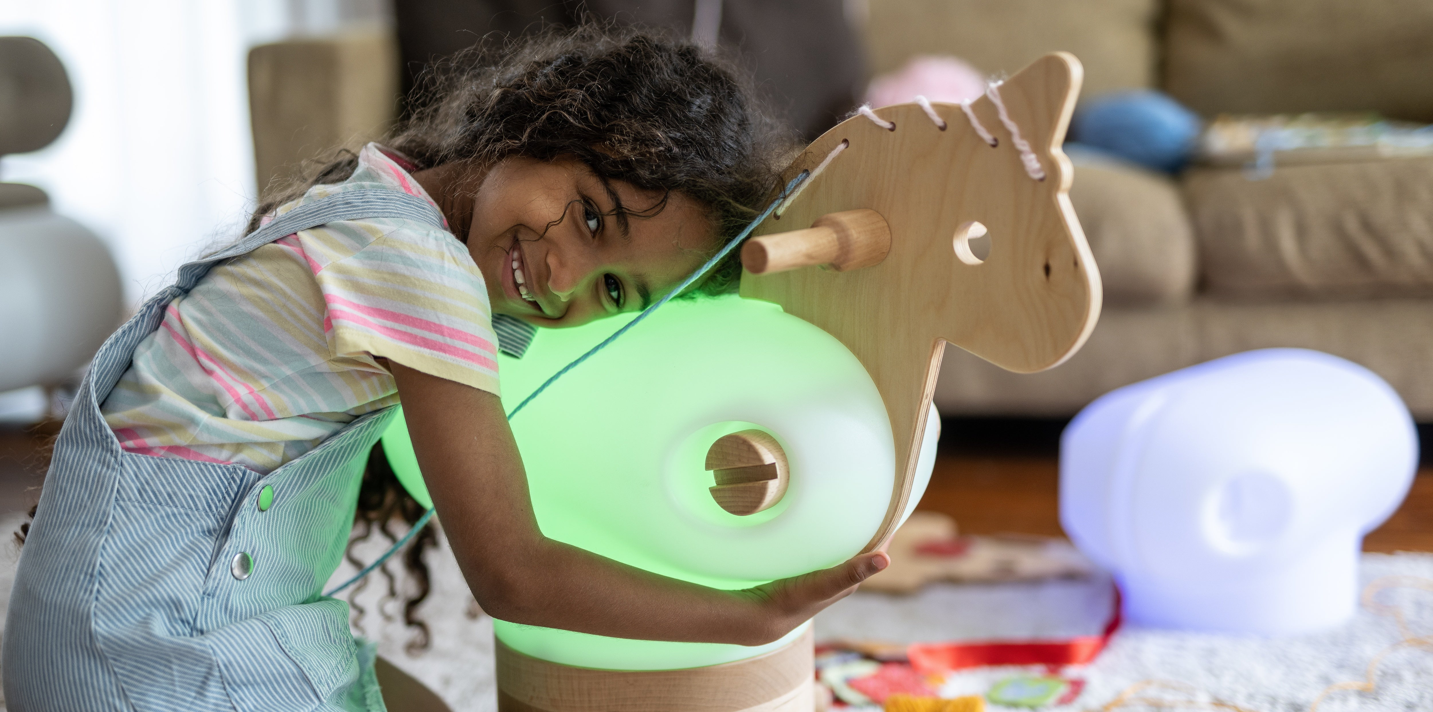 Little girl hugging a wood Anfa horse