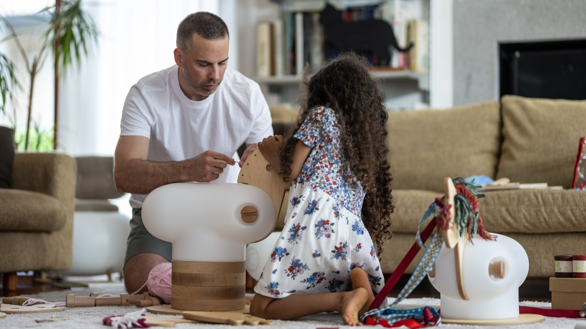 man and little girl playing with an anfa wooden horse