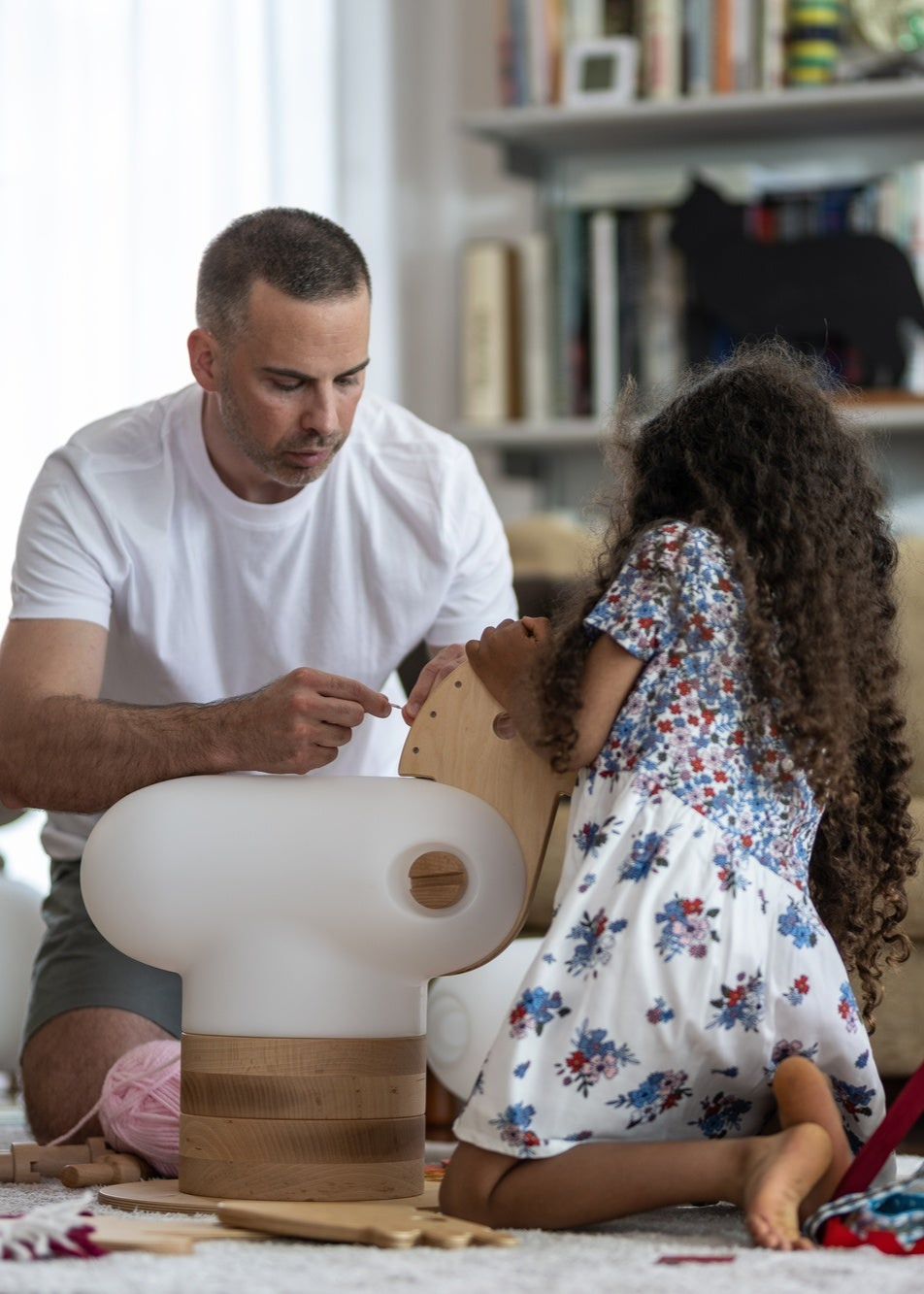 man and little girl playing with an anfa wooden horse