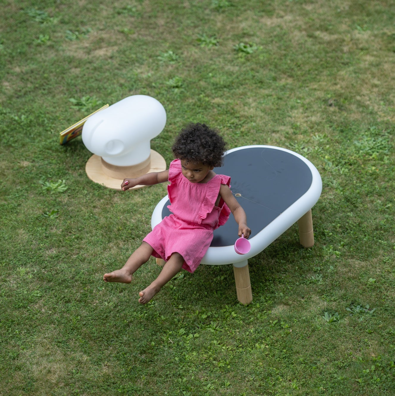 little girl playing in the garden with an under construction horse and a table