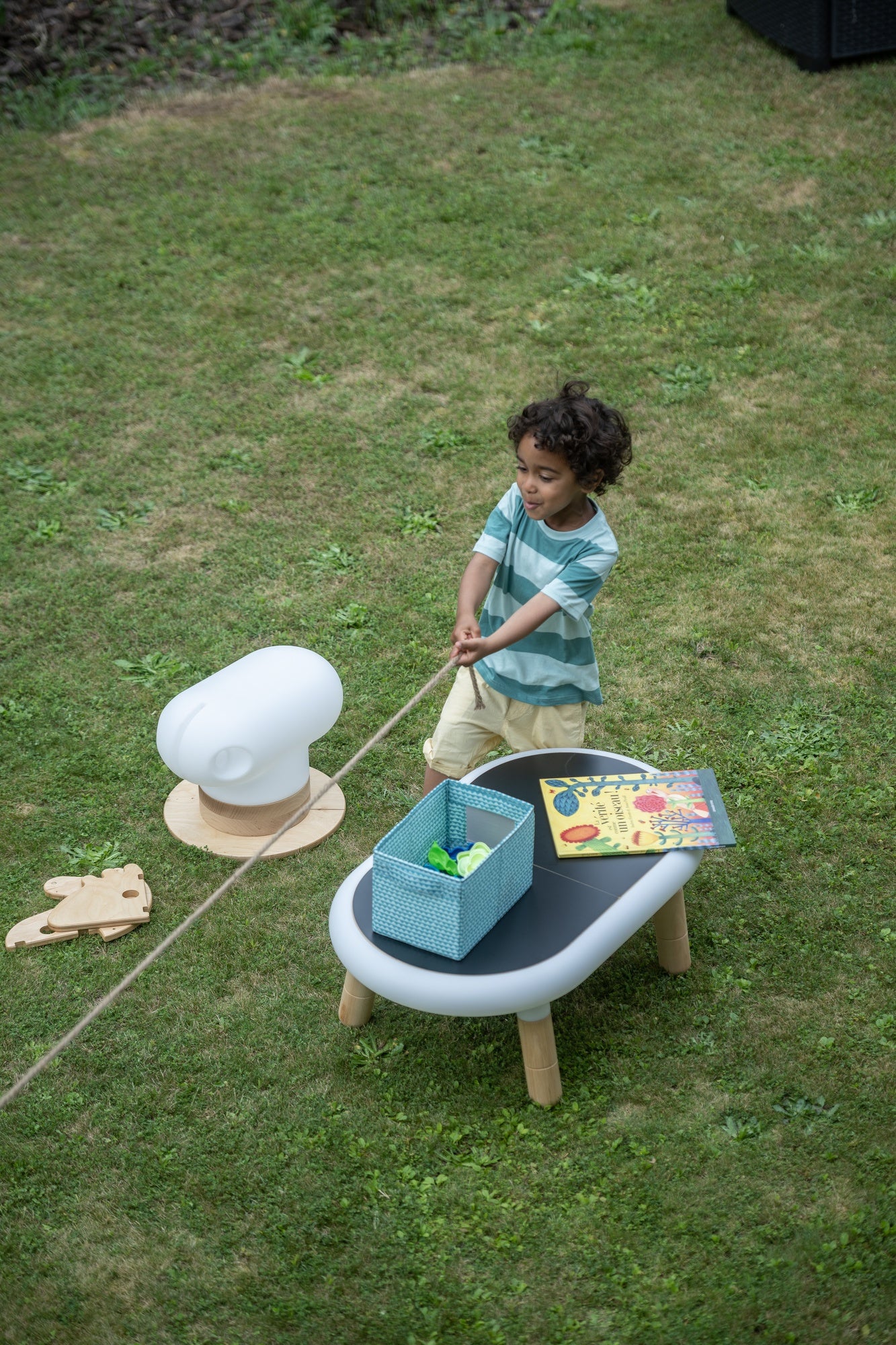 Little boy plaing in the garden with a wood horse and a table