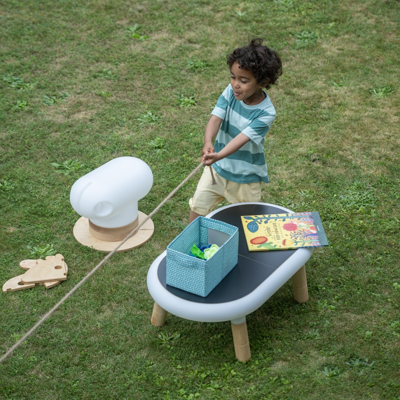 little boy playing in the garden with an under construction horse and a table