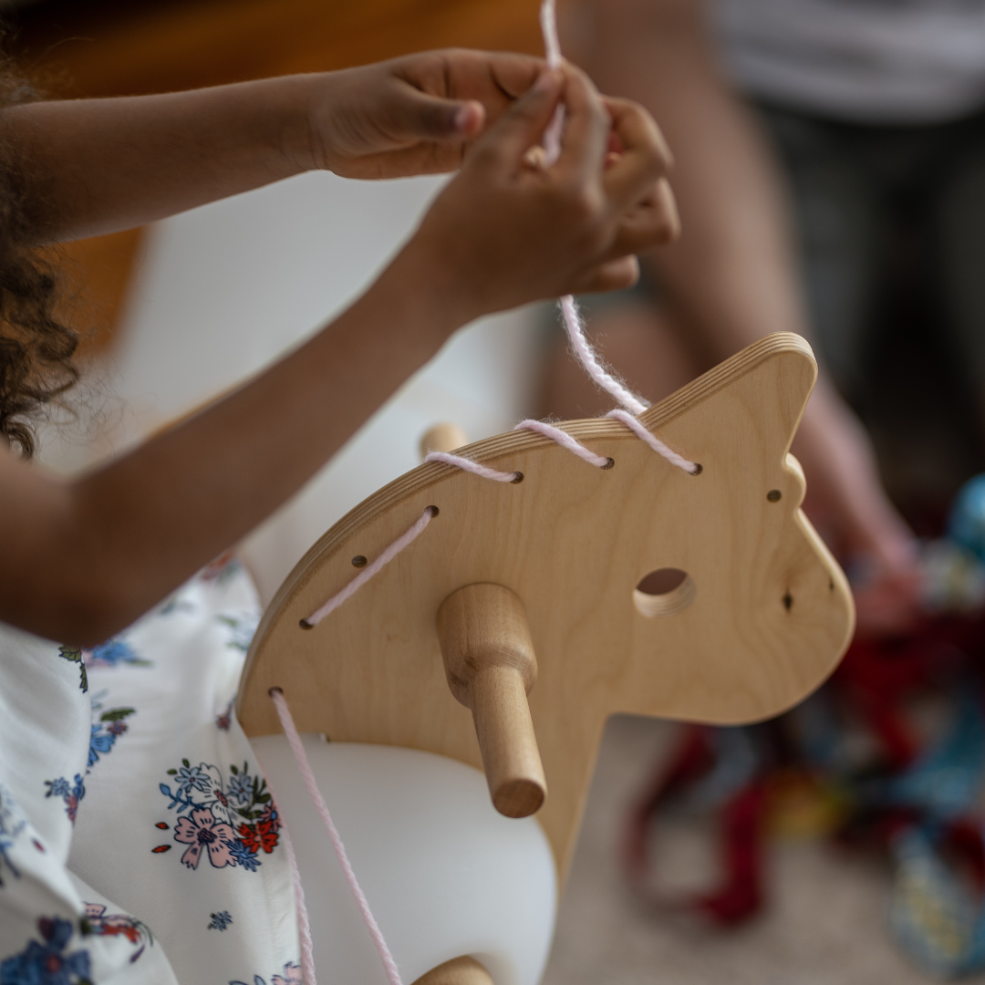 girl playing with textiles and wooden horse